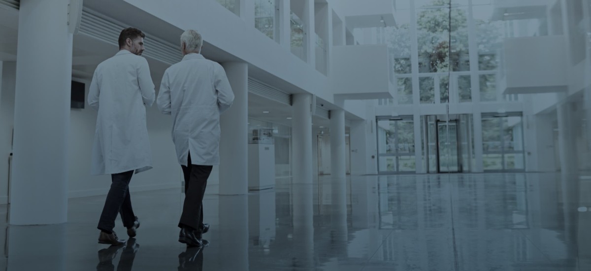 Two doctors or men in lab coats walking through a hospital lobby