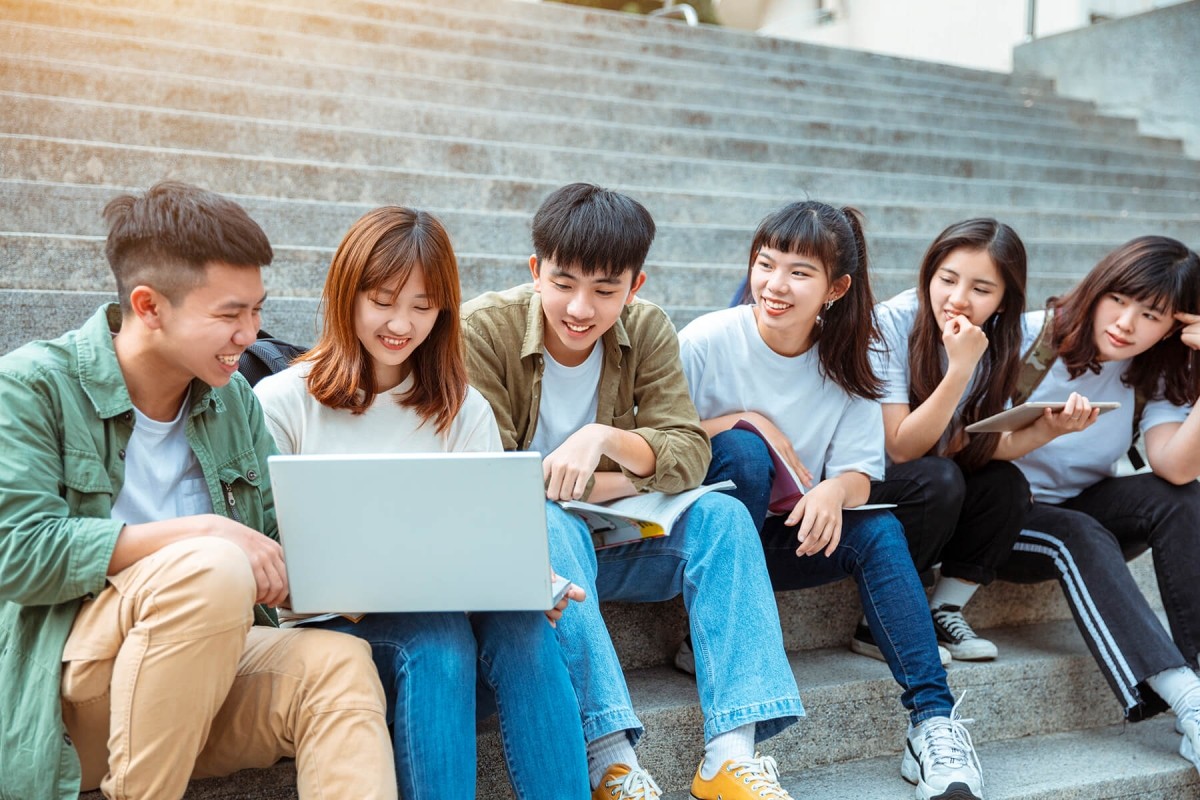 Asian students sitting on steps looking at a laptop