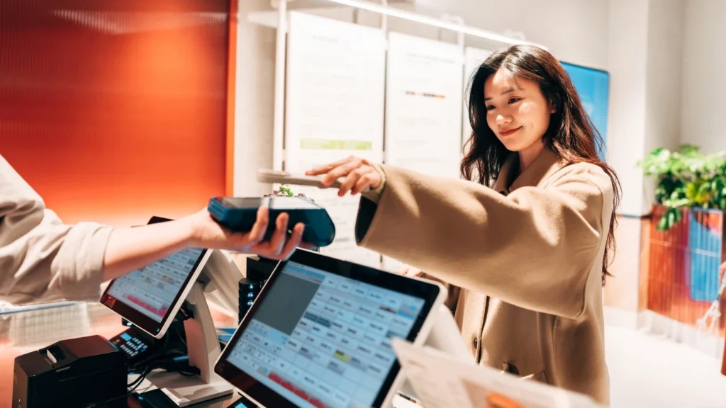 Female retail shopper using her phone to pay for a purchase